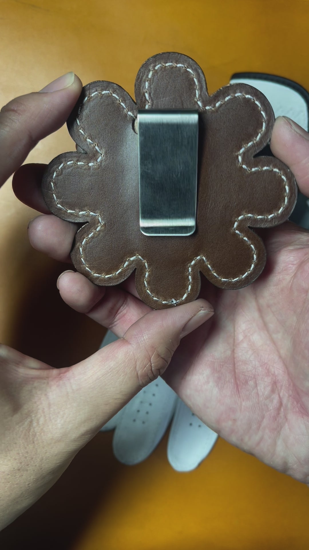 Close up video of Daisy Clip-on golf glove holder. Showing front Pebbled white lether and back brown leather with stainless steel clip