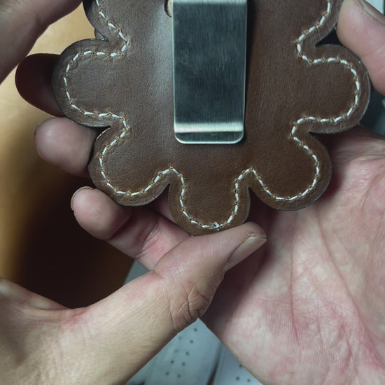 Close up video of Daisy Clip-on golf glove holder. Showing front Pebbled white lether and back brown leather with stainless steel clip